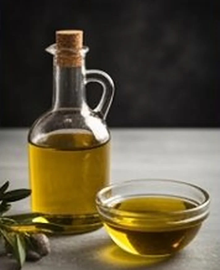 Botellita y cuenco de aceite de oliva con ramas de olivo