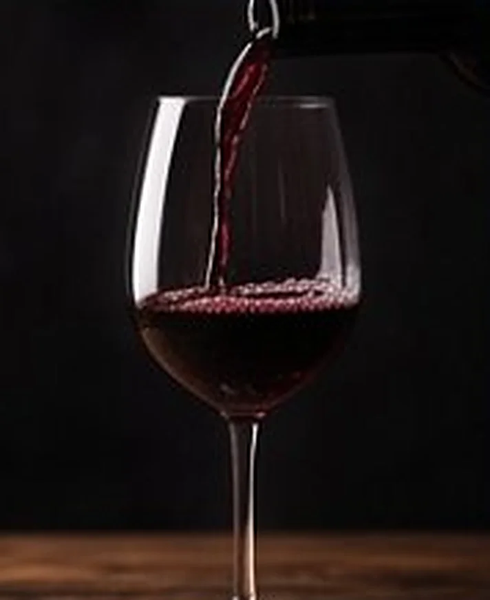 Vino tinto servido en una copa sobre mesa de madera
